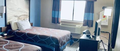 Habitación de hotel con dos camas, un escritorio, una silla, un televisor y una ventana con cortinas.
