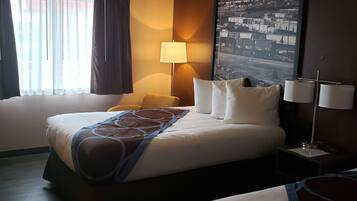 Quarto de hotel com duas camas, uma janela grande com cortinas, uma luminária na parede e uma pintura com vista para a cidade.