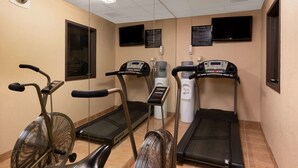 Un gimnasio equipado con cintas de correr, elípticas y un dispensador de agua.