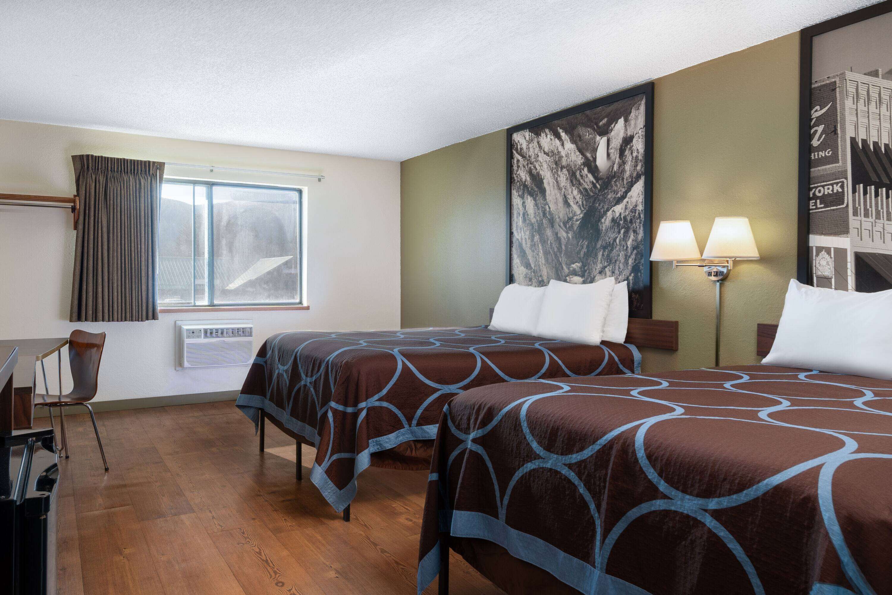 A hotel room with two beds, a desk, and a chair.