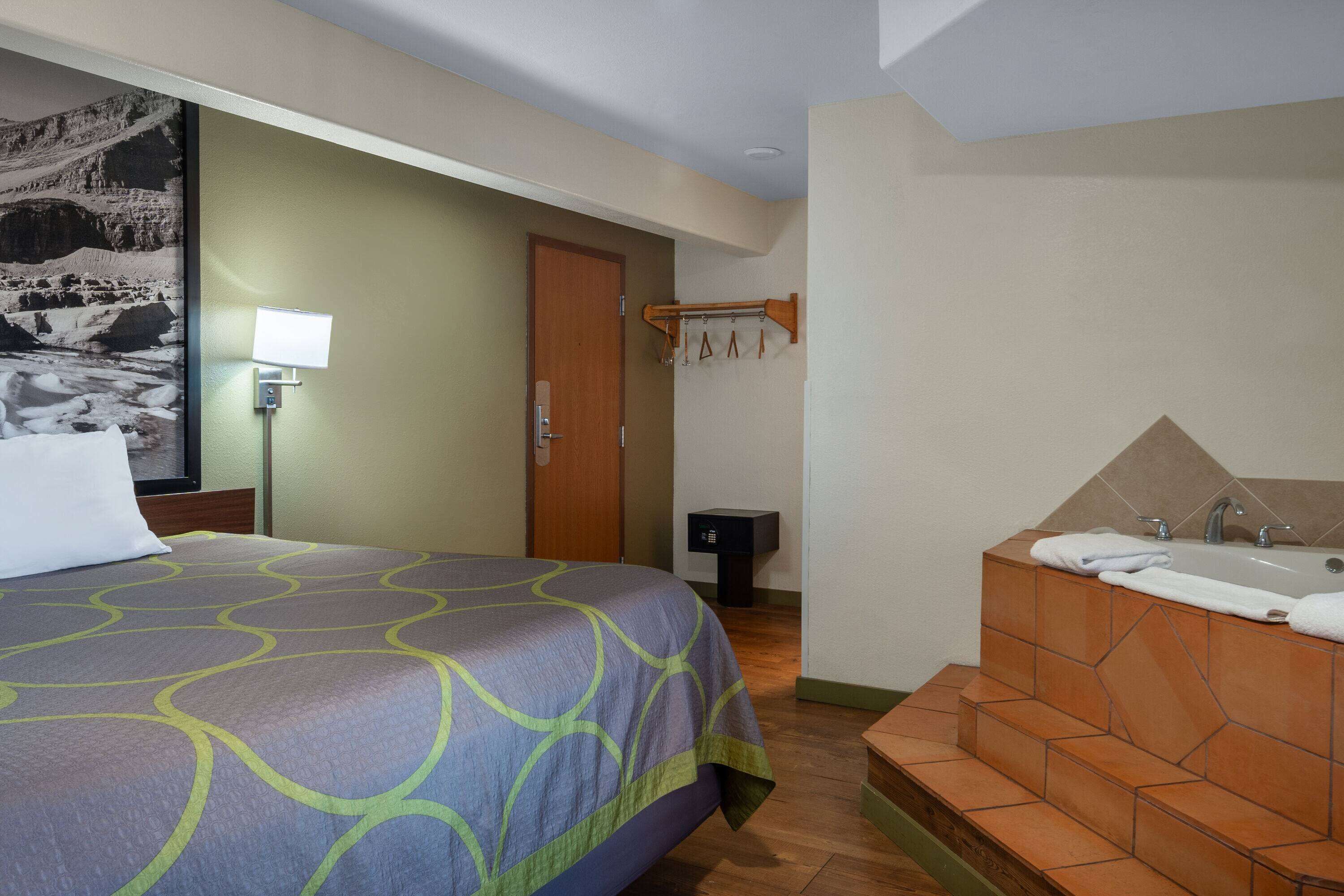 A hotel room with a bed, a bathroom with a bathtub, and a wall-mounted towel rack.