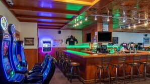 A bar area with arcade games, a counter, and bar stools. - Super 8 by Wyndham Livingston Yellowstone (Livingston)