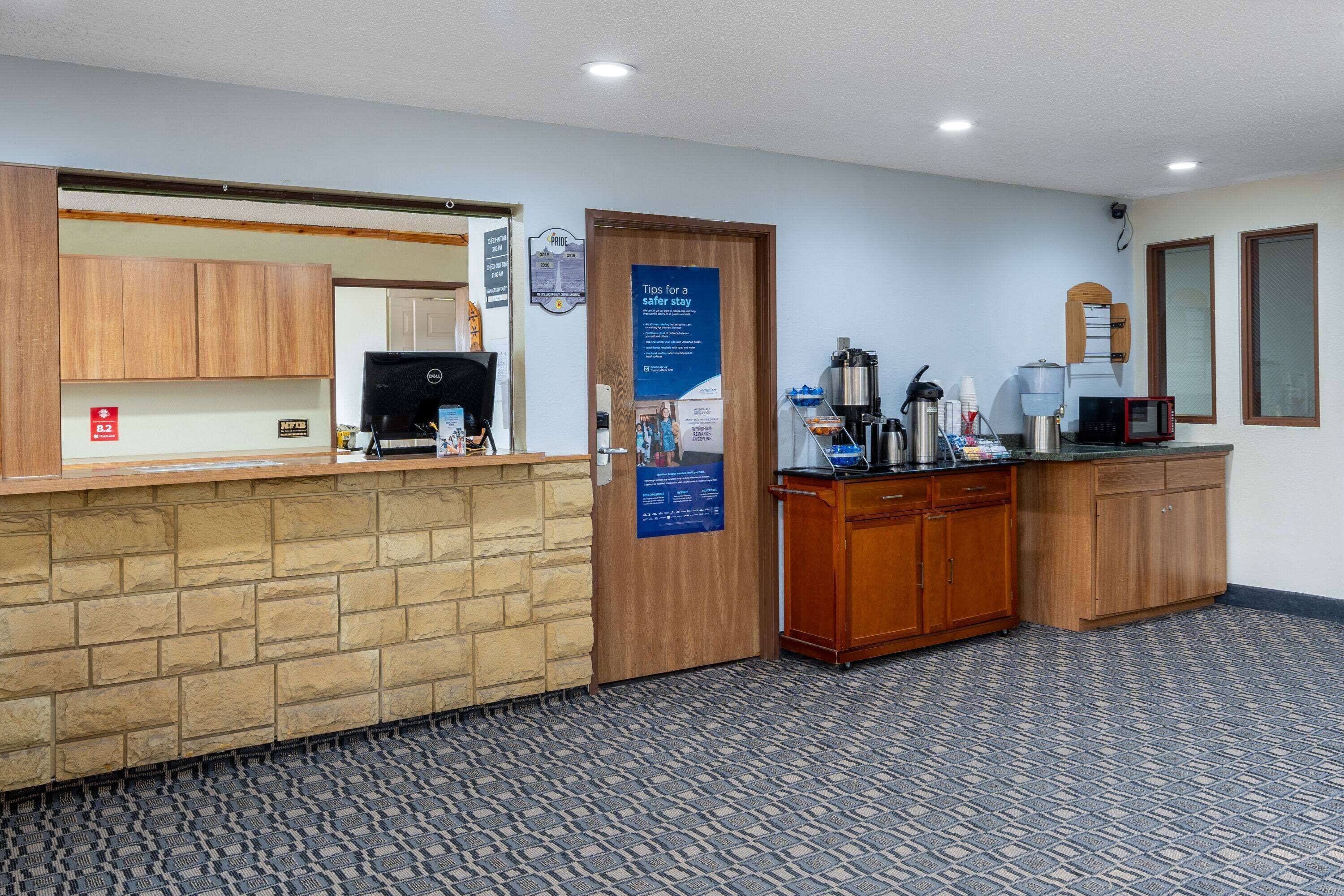 A reception area with a stone counter, wooden cabinets, a coffee station, and a door with a safety tip poster.