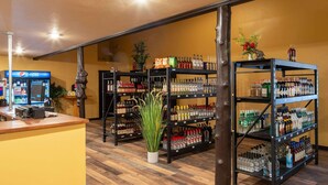 A bar area with shelves stocked with various liquor bottles, a Pepsi refrigerator, and a wooden counter. - Super 8 by Wyndham Livingston Yellowstone (Livingston)