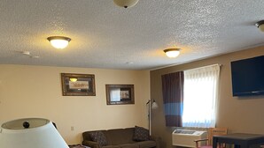 Une chambre d’hôtel équipée d’un lit, d’un bureau, d’une chaise, d’une lampe, d’une télévision et d’une fenêtre avec des rideaux.