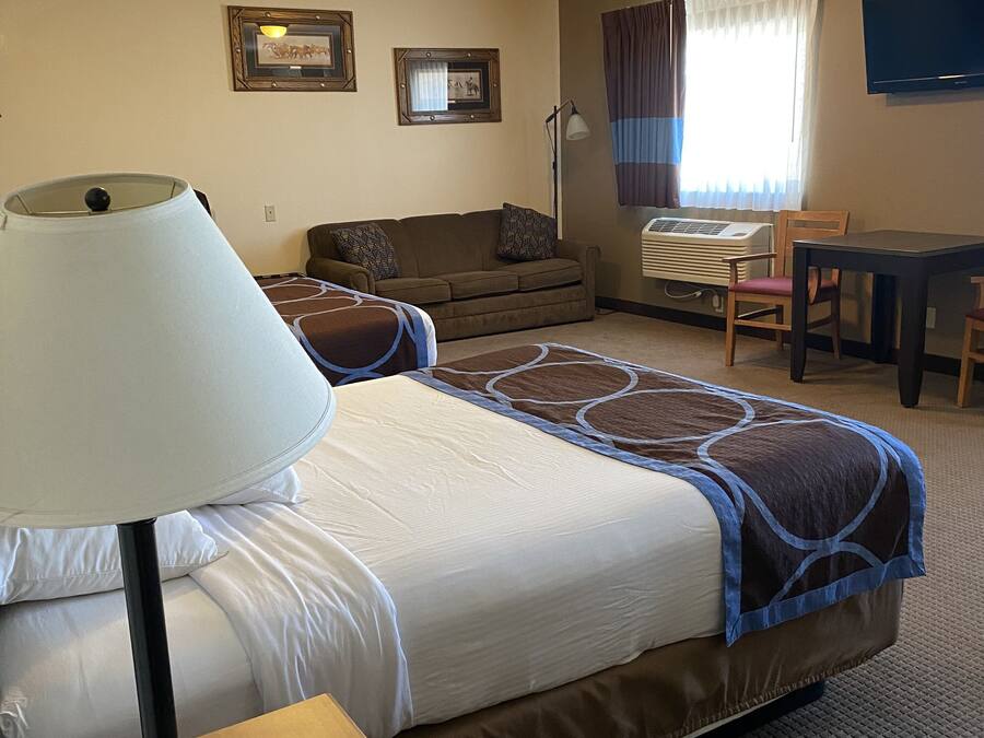A hotel room with a bed, a desk, a chair, a lamp, a TV, and a window with curtains.