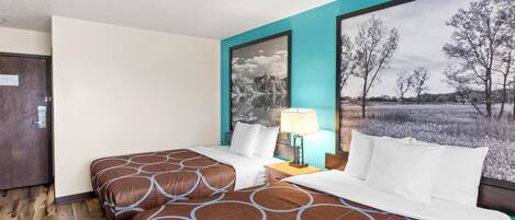 Une chambre d’hôtel avec un lit double, une table de chevet avec une lampe et un grand tableau représentant un paysage accroché au mur.