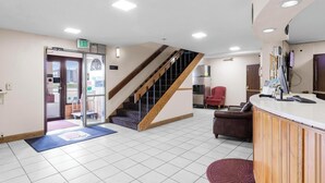 Un espace d’accueil comprenant un comptoir de réception, un escalier et un fauteuil rouge.