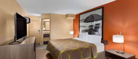 A hotel room with a bed, a TV, a desk, and a painting on the wall.