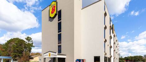 A Super 8 hotel with a modern facade, a parking lot, and a clear blue sky.