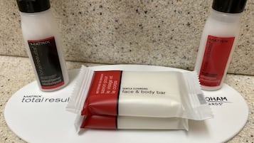 Une assiette blanche contenant un pain de savon pour le visage et le corps, deux flacons de shampoing et une étiquette portant la marque « Matrix ».