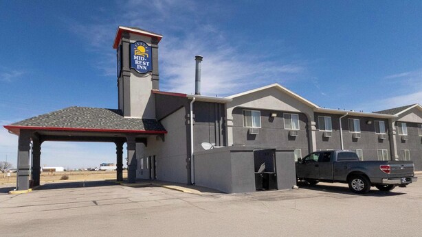 A motel with a covered entrance, a truck parked outside, and a clear sky.