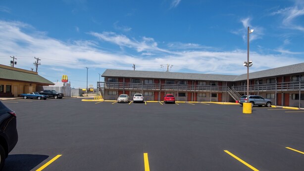 A parking lot with several cars, a building with a McDonald's sign, and a clear blue sky.