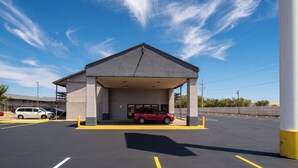 A parking garage entrance with a covered area, marked parking spaces, and a red vehicle parked inside.