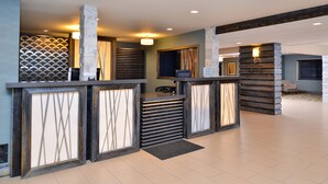 Un espace d’accueil au design moderne, comprenant un comptoir de réception, un coin salon et des panneaux muraux décoratifs.