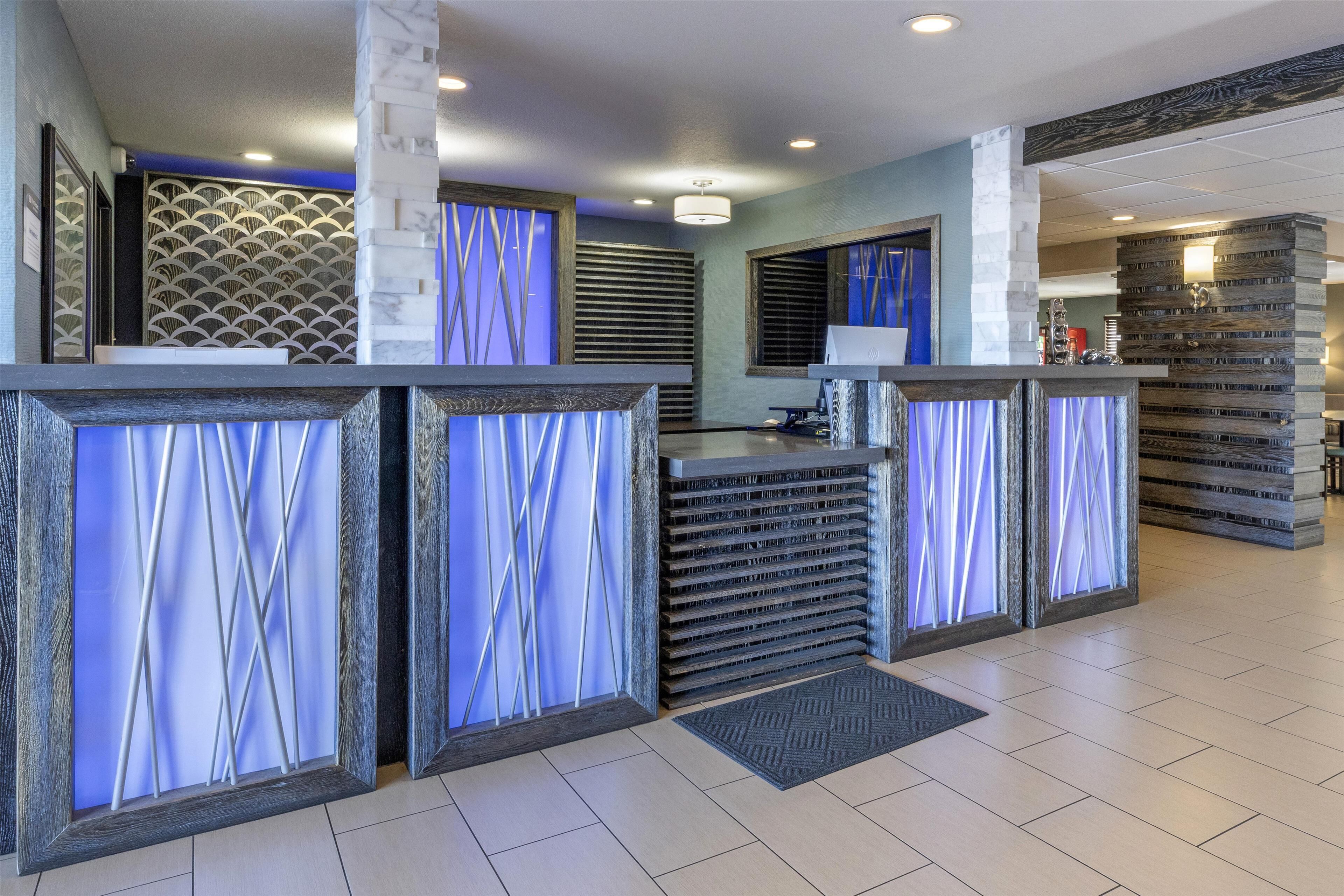 A reception area with a modern design, featuring a reception desk, a seating area, and a decorative wall with a geometric pattern.