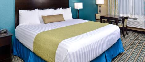 Una habitación de hotel con una cama grande, dos mesitas de noche, un escritorio y una silla.