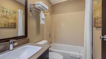 Een badkamer met een wastafel, toilet en bad. Er is een handdoekrek met handdoeken en een douchegordijn.