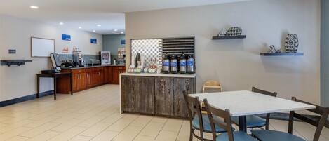 A hotel lobby with a reception desk, a small bar area, and a dining area with a table and chairs.