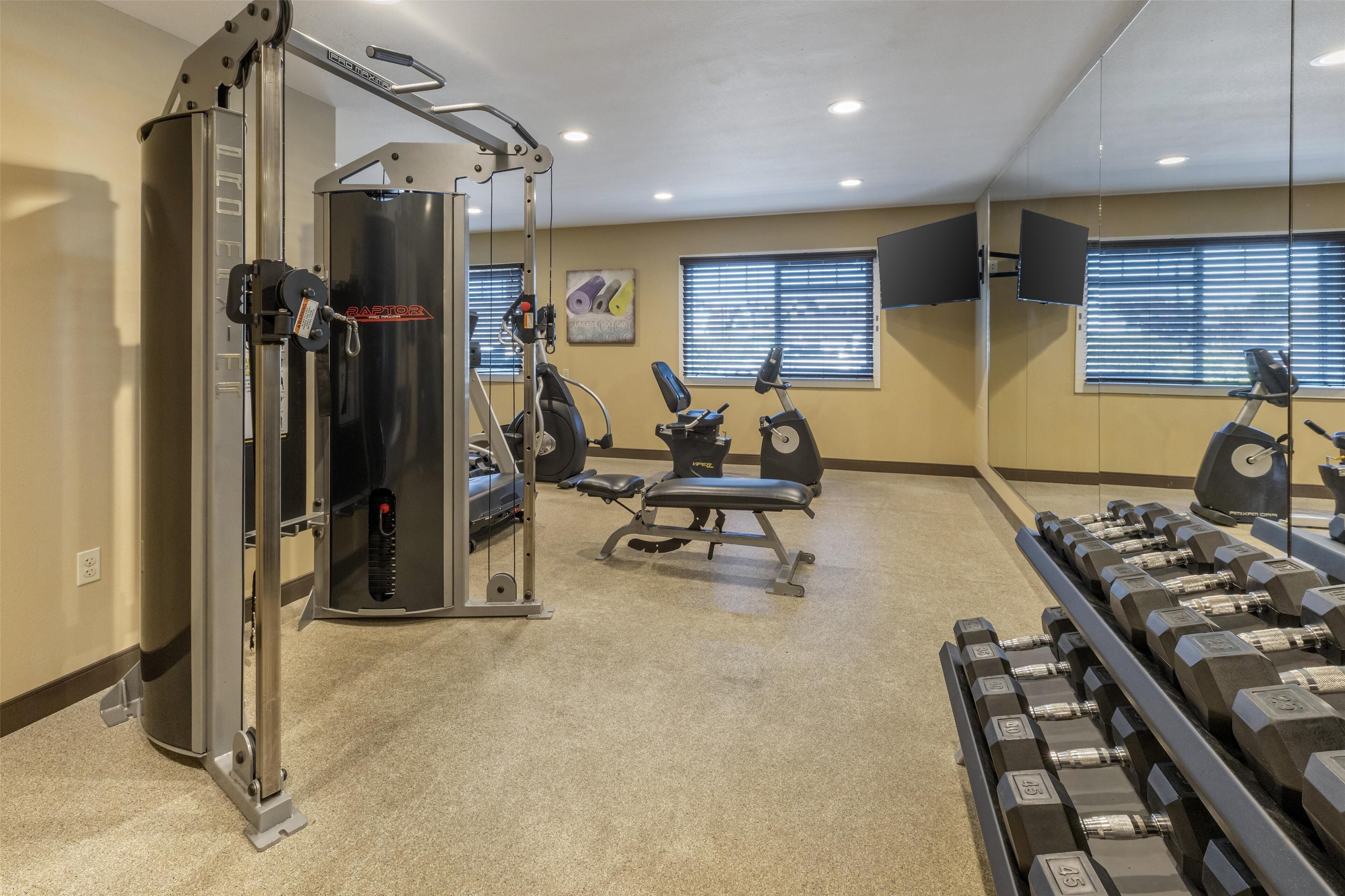 Uma academia com equipamentos de exercícios, um banco e halteres.