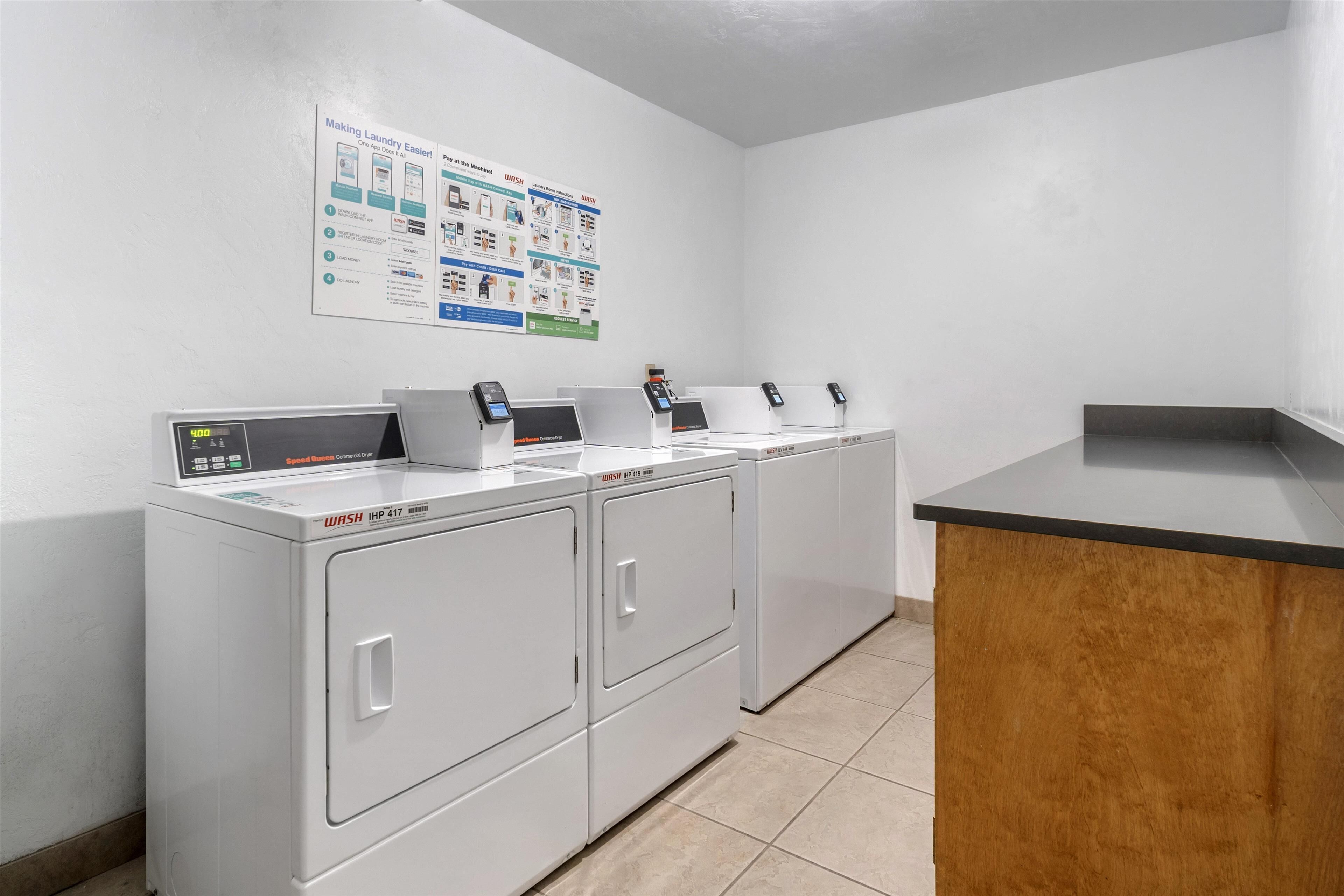 Eine Wäscherei mit vier Waschmaschinen mit Frontlader, einer Holzausstattung und einem Poster an der Wand.
