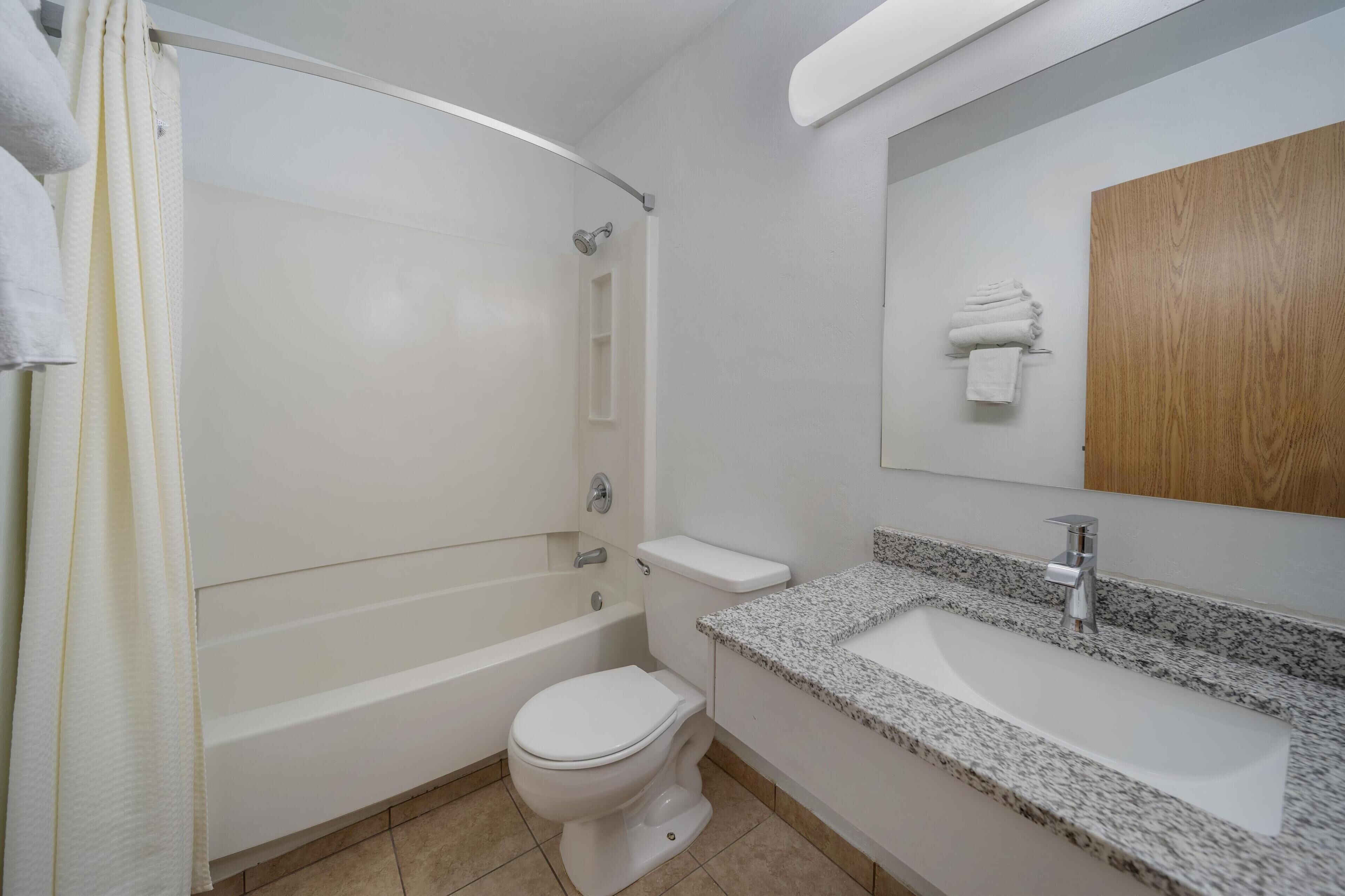 A bathroom with a bathtub, toilet, sink, and a wooden cabinet.
