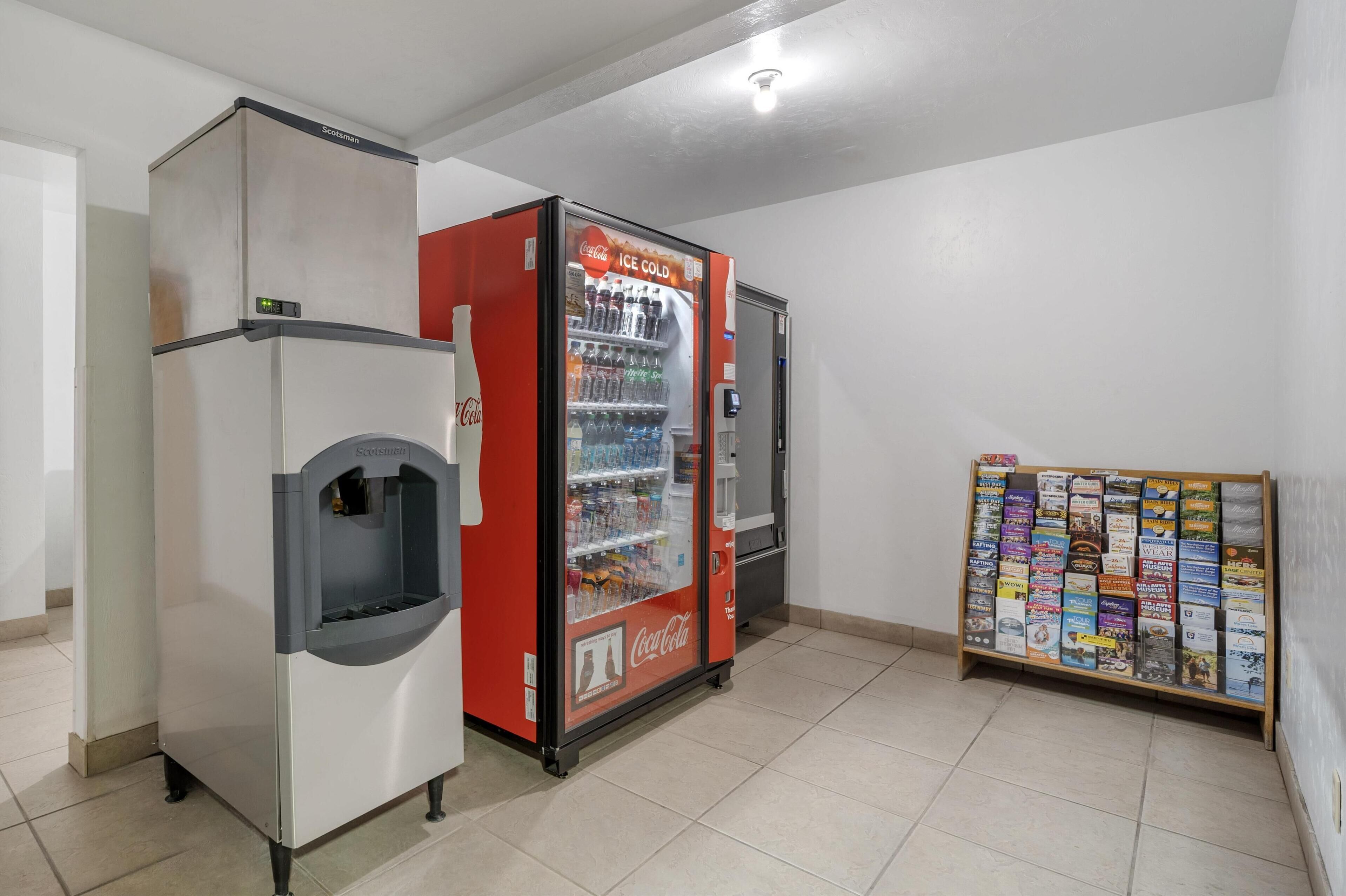 A vending machine with a Coca-Cola logo, a refrigerator, and a display rack with brochures.