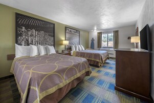 A hotel room with two beds, a flat-screen TV, a desk, and a large window with curtains.