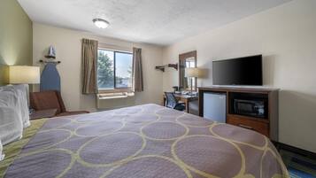 A hotel room with a large bed, a desk with a computer, a TV, and a microwave.