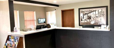 A reception area with a desk, computer, and a framed welcome sign.