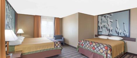 A hotel room with two beds, a desk with a lamp, a chair, and a large painting on the wall.