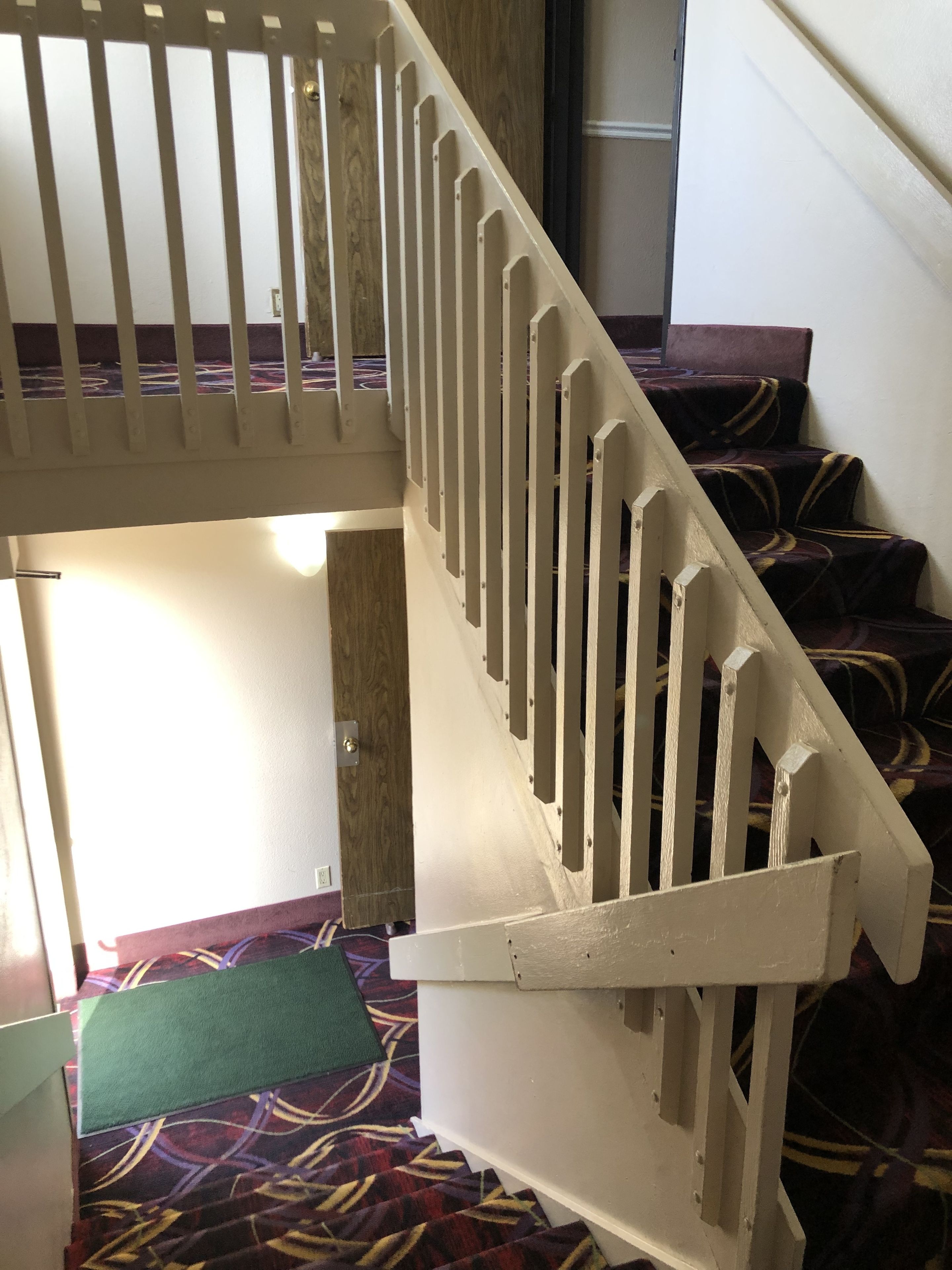 A staircase with white railings and a patterned carpet.