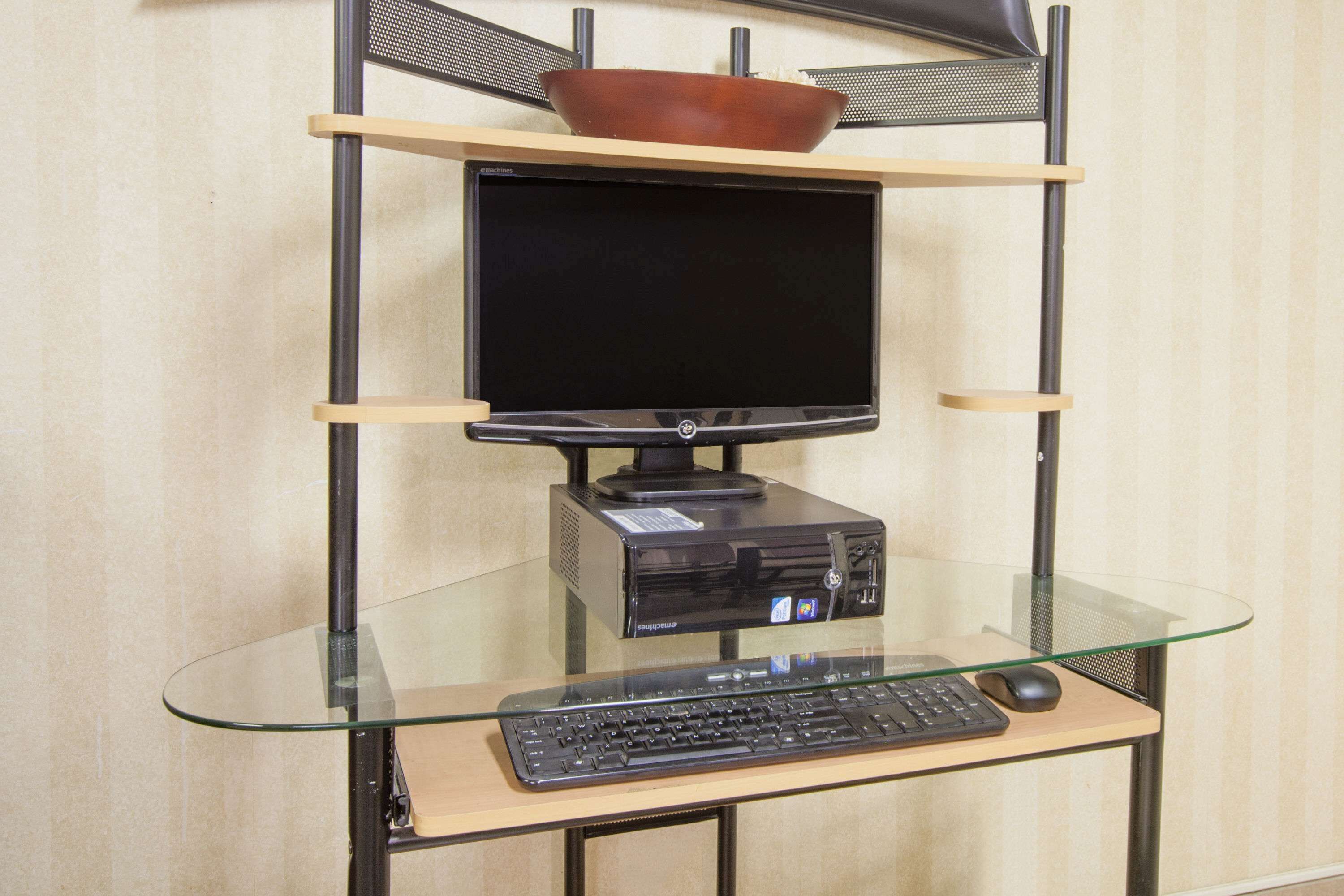 A computer desk with a monitor, keyboard, and mouse.