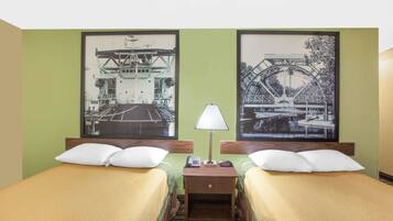 A hotel room with two beds, a nightstand with a lamp, and two framed pictures of bridges.