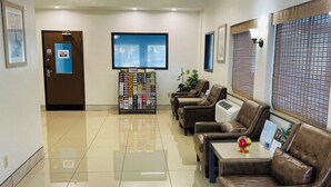A lobby with a reception desk, seating area, and a wall-mounted TV. - Super 8 by Wyndham Lacey Olympia Area (Lacey)