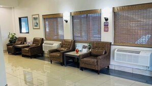 A reception area with leather chairs, a reception desk, and a large window with blinds. - Super 8 by Wyndham Lacey Olympia Area (Lacey)