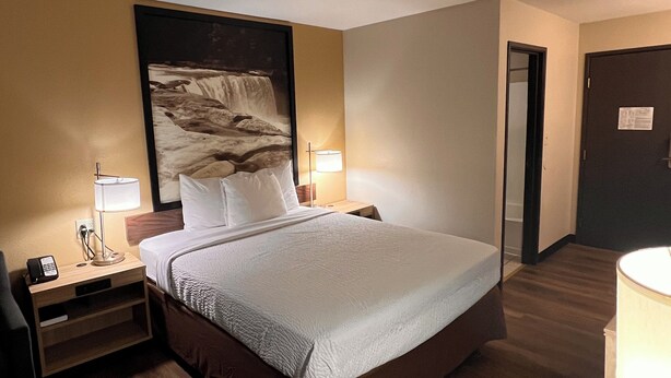 A hotel room with a bed, bedside tables, a desk, and a chair. - Super 8 by Wyndham Radcliff Ft. Knox Area (Radcliff)