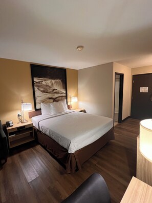 Una habitación de hotel con una cama, mesitas de noche, un escritorio y una silla.