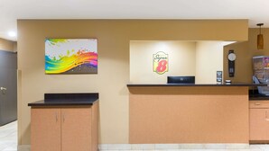 A reception area with a counter, a clock, and a colorful abstract painting on the wall. - Super 8 by Wyndham Radcliff Ft. Knox Area (Radcliff)