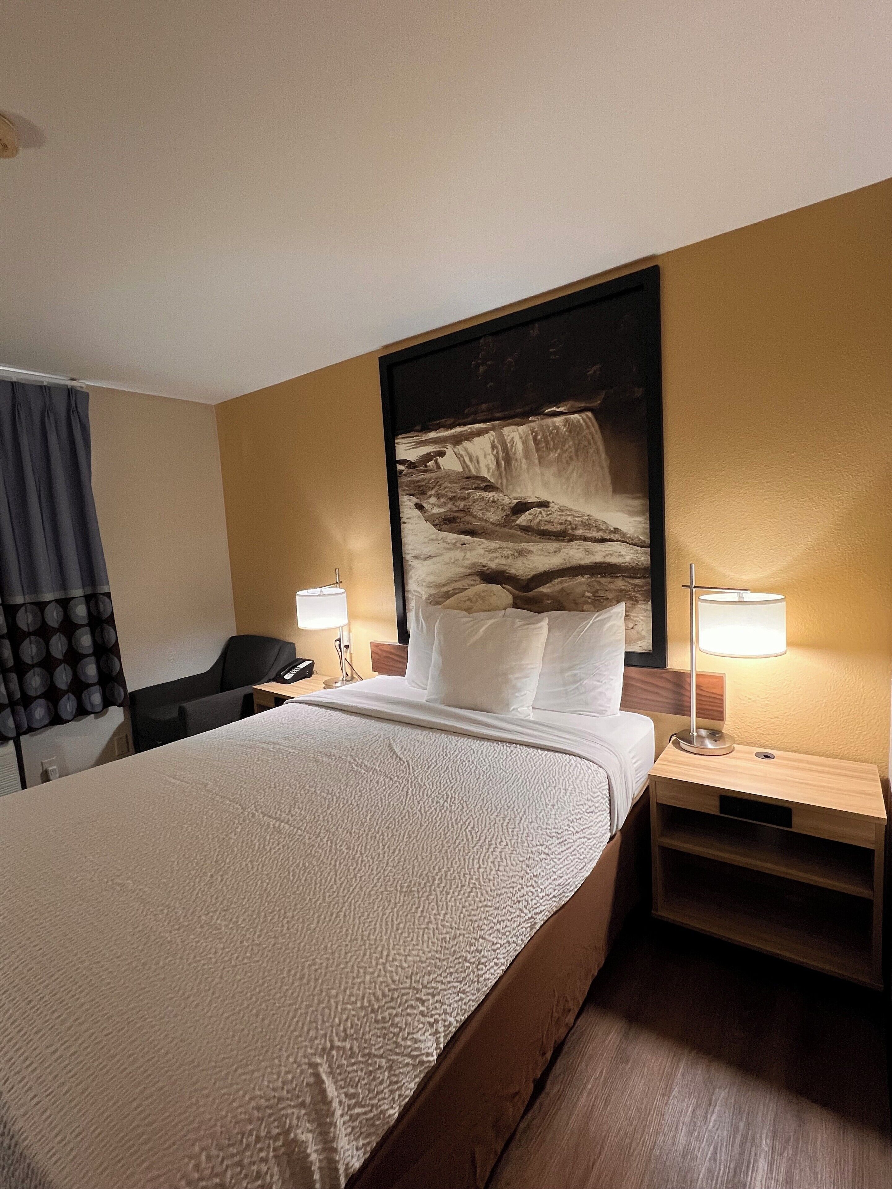 A hotel room with a large bed, two bedside tables, a desk, and a chair.
