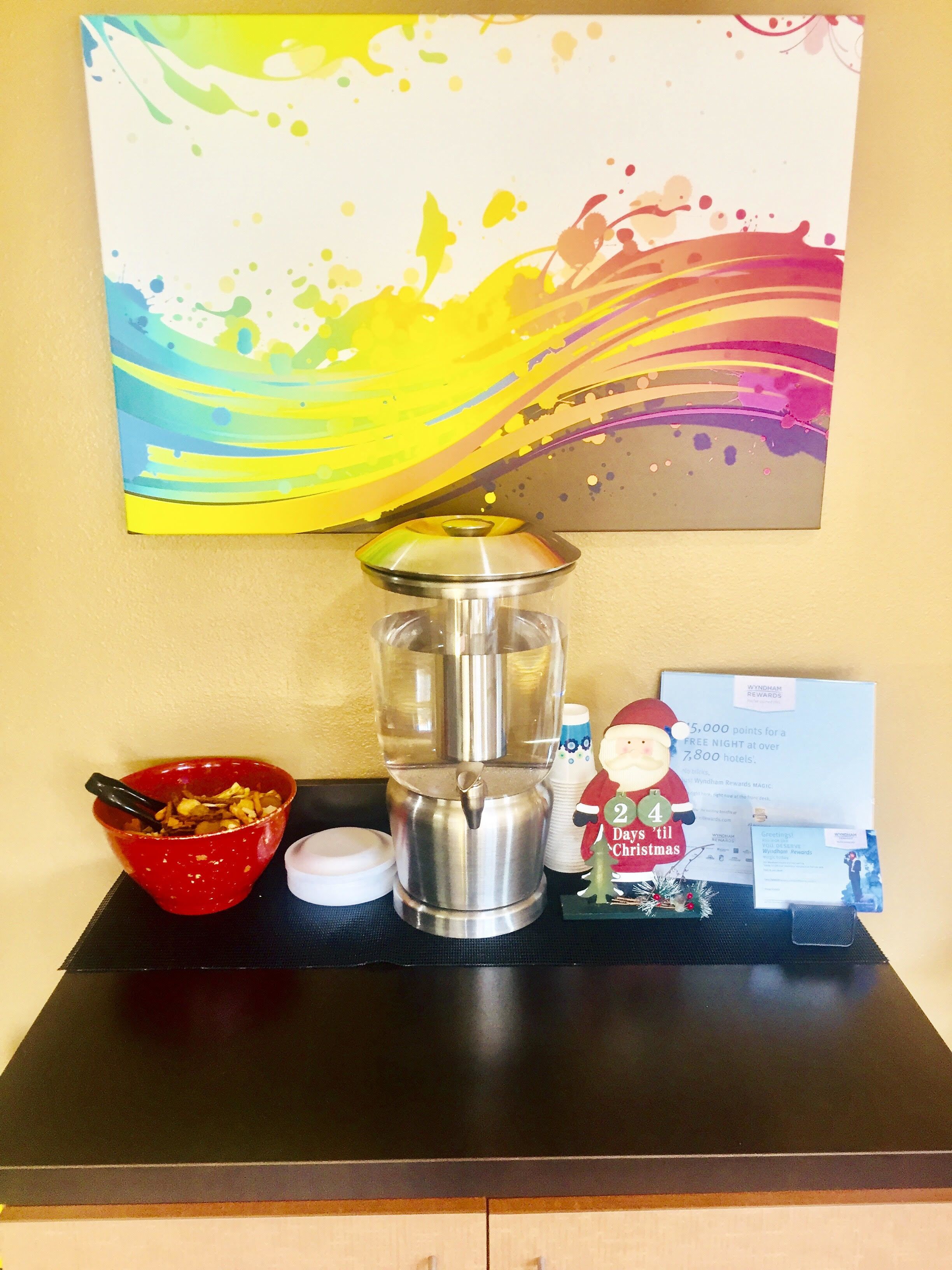 A coffee maker, a red bowl with food, a decorative Santa figurine, and a Wyndham Rewards card on a table.