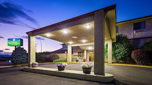A SureStay by Best Western hotel entrance with a covered fuel pump area, outdoor seating, and potted plants. - SureStay Hotel by Best Western Ellensburg (Ellensburg)