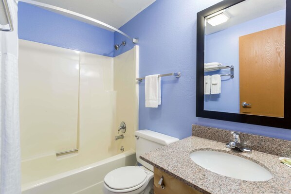 A bathroom with a bathtub, toilet, sink, and a mirror. - Super 8 by Wyndham Douglas (Douglas)