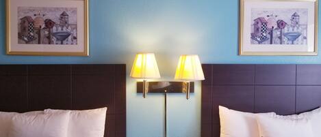 Una habitación de hotel con dos camas, una mesita de noche y dos lámparas de pared.