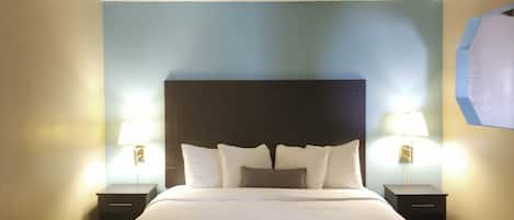 A hotel room with a large bed, two bedside tables, and two wall-mounted lamps.
