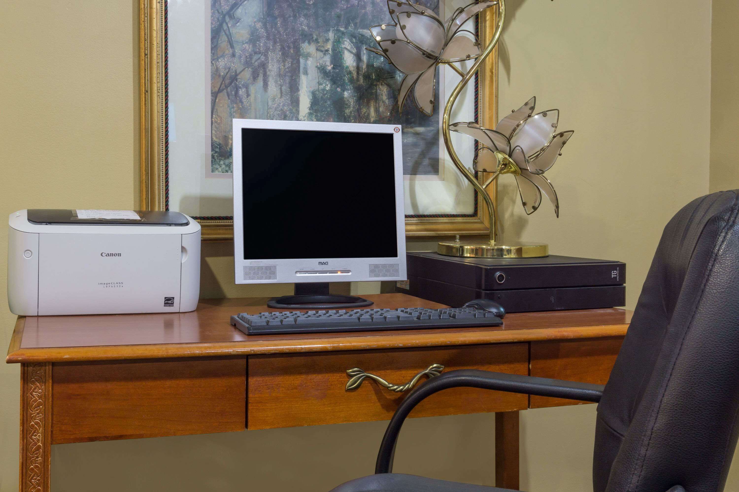 A wooden desk with a desktop computer, a Canon printer, and a keyboard.