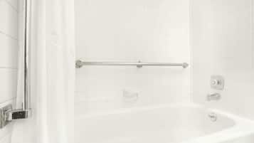 Eine weiße Badewanne mit chromfarbenen Armaturen und einer Haltestange.