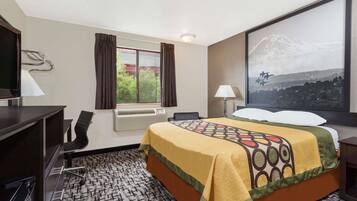 A hotel room with a bed, desk, chair, and a large window with curtains.