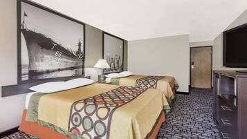 A hotel room with two beds, a cityscape painting, a television, and a wooden door.