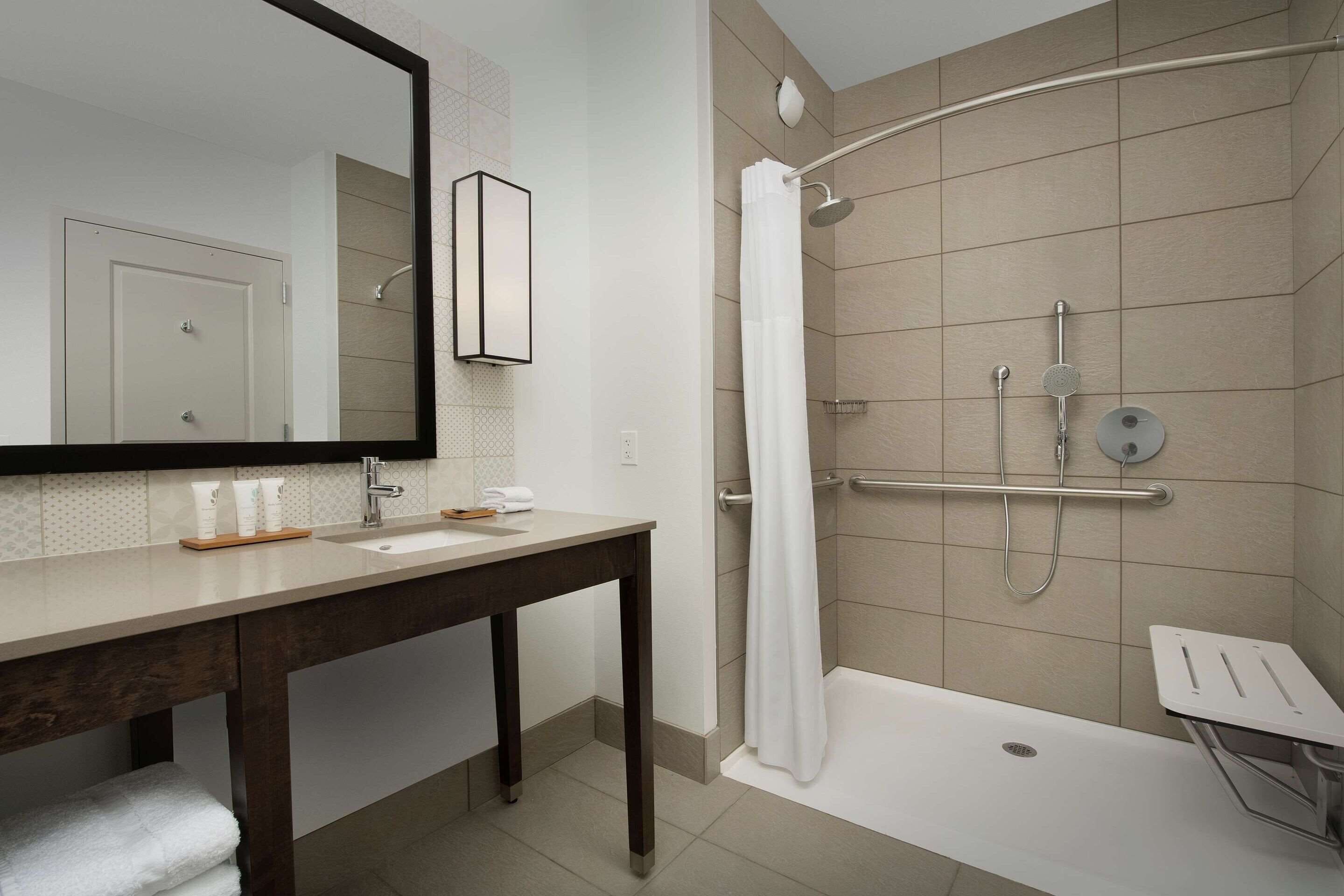 A modern bathroom with a shower, a sink, and a mirror.